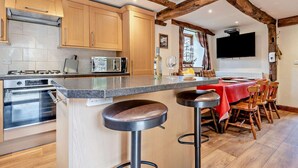 Une cuisine avec des poutres en bois, un coin bar et un espace repas avec une nappe rouge.