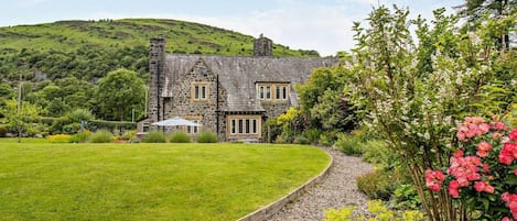 A stone house with a well-maintained lawn and garden.