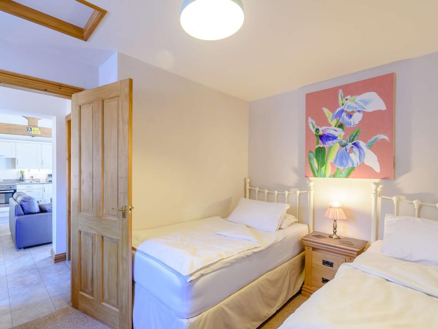 A bedroom with a bed, bedside table, and a painting of flowers.