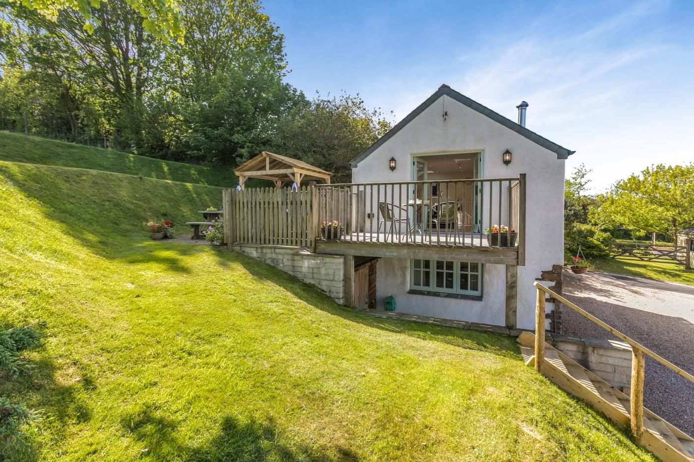 A two-story house with a balcony, a stone wall, and a wooden fence.