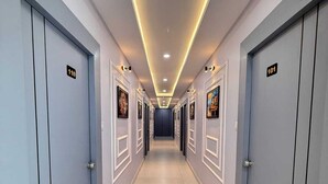 A hotel corridor with doors numbered 101 and 110, recessed lighting, and framed pictures on the walls.