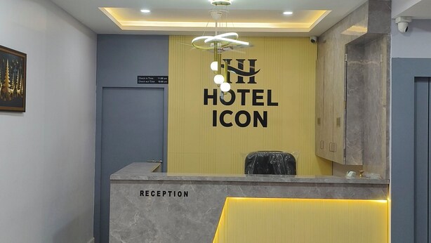 A hotel reception area with a reception desk, a ceiling fan, recessed lighting, and a wall-mounted sign.