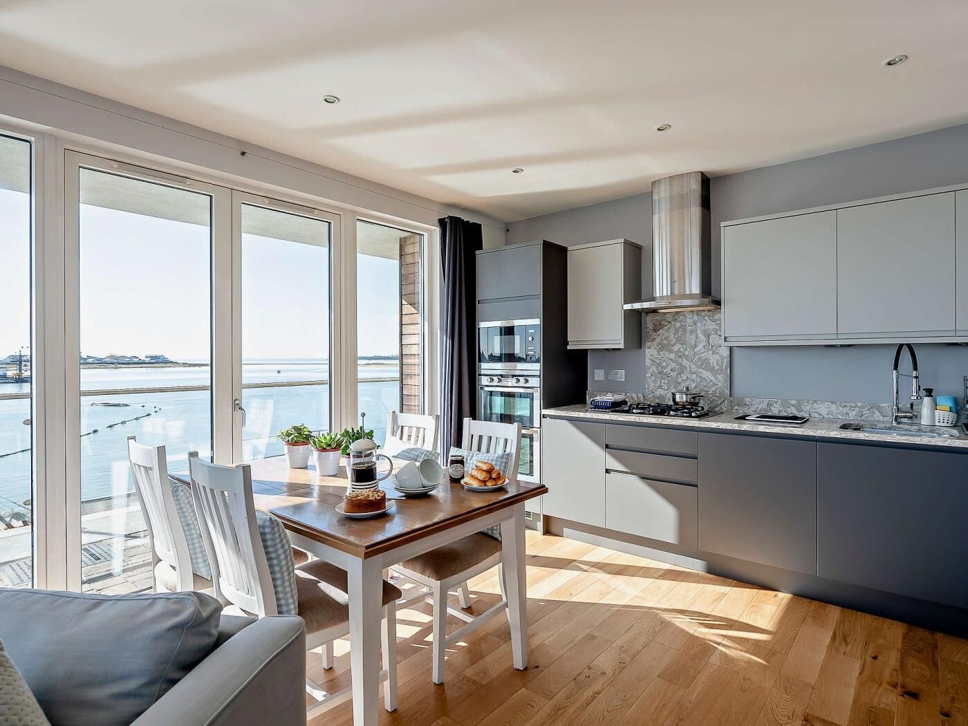 Une cuisine moderne avec vue sur l’eau, un coin repas avec une table et des chaises, et un canapé.