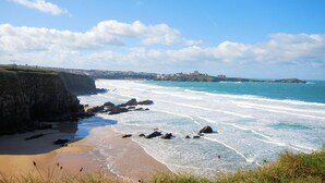 A coastal landscape with a beach, rocky shoreline, and distant buildings. - 2 Bed in Truro (oc-ljasm) (Tregavethan)
