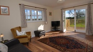 A living room with a sofa, armchair, television, and a large rug. - 2 Bed in Truro (oc-ljasm) (Tregavethan)