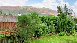 Una proprietà residenziale con vista sulle montagne, una recinzione in legno e un giardino curato.