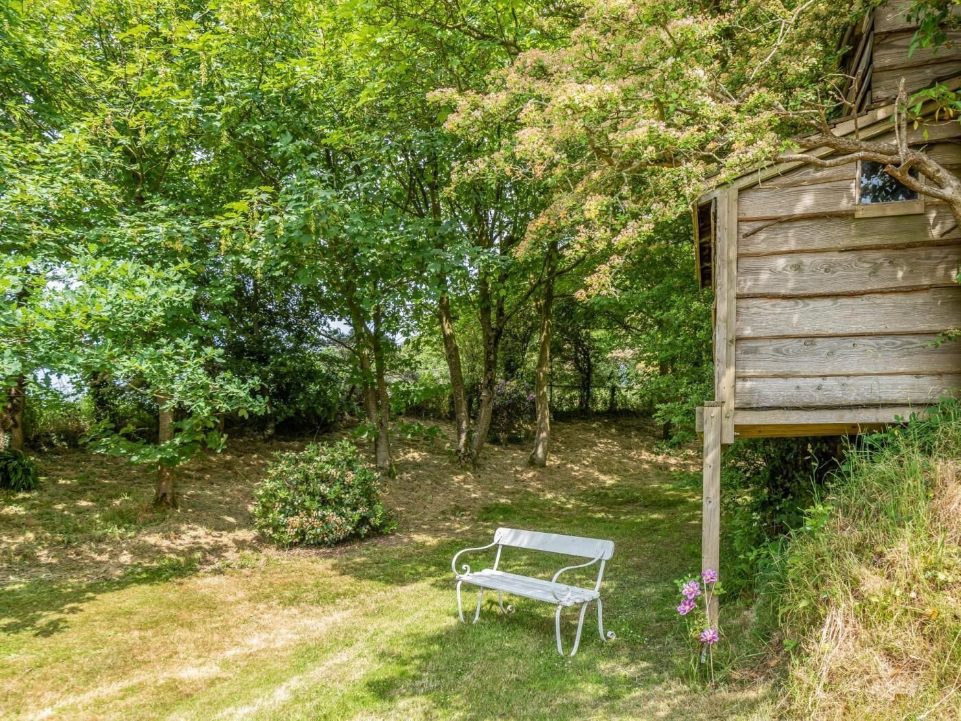 Eine Holzhütte mit einer Bank in einem üppigen Garten.