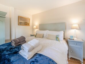 A neatly made bed with white and blue bedding, two bedside lamps, a small bedside table with a lamp, and a framed picture on the wall. - 2 Bed in Holsworthy (oc-32154) (North Tamerton)