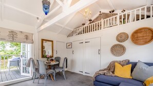 A room with a dining area, a sofa, and a staircase. - 2 Bed in Holsworthy (oc-32154) (North Tamerton)