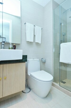 Un bagno moderno con WC, lavandino e cabina doccia in vetro.