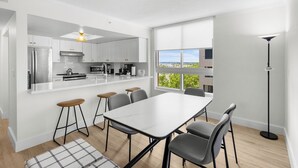 A modern kitchen with white cabinets, a stainless steel refrigerator, and a large window offering a view. - Signature Luxury 2/2 Condo Retreat (Miami)