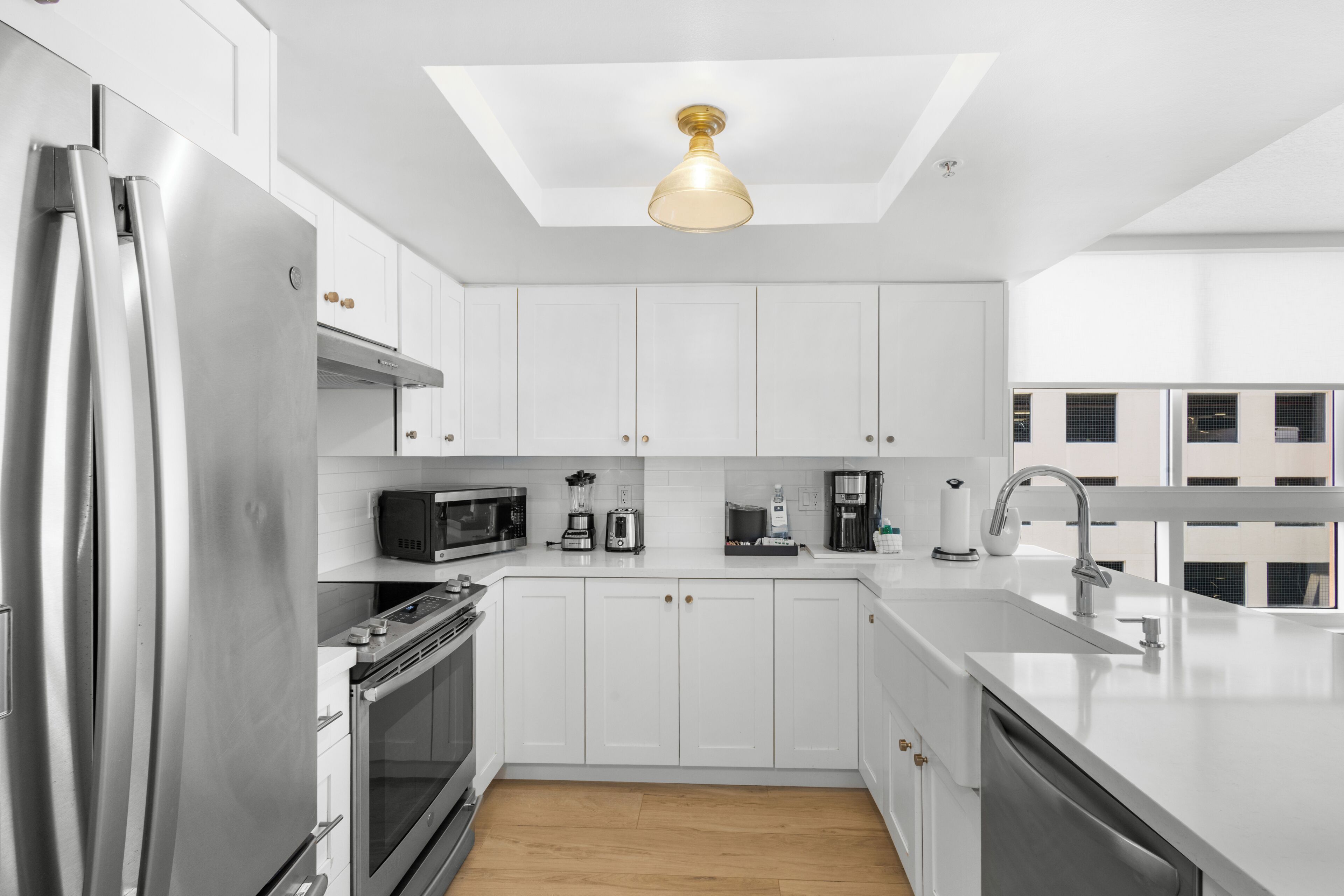 A modern kitchen with white cabinets, stainless steel appliances, a central island, and a skylight.