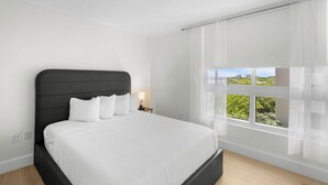 A modern bedroom with a large bed, a nightstand, a window with a view, and a white ceiling. - Signature Luxury 2/2 Condo Retreat (Miami)