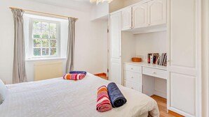 A bedroom with a bed, a desk, and a wardrobe.