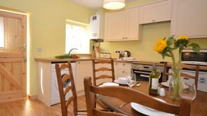 A kitchen with wooden cabinets, a dining table with chairs, a washing machine, and a sink. - 2 Bed in North Walsham (oc-29570) (Worstead)