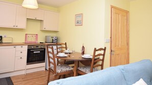 A compact kitchen with a dining table, chairs, and a microwave. - 2 Bed in North Walsham (oc-29570) (Worstead)