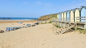 A beach with wooden walkways leading to beach huts, a sandy beach, and the ocean in the background. - 3 Bed in Holsworthy (oc-29125) (Thornbury)