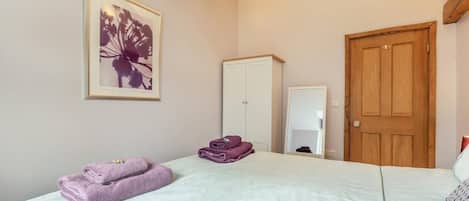 Une chambre à coucher avec un lit, une armoire, un miroir et une porte.