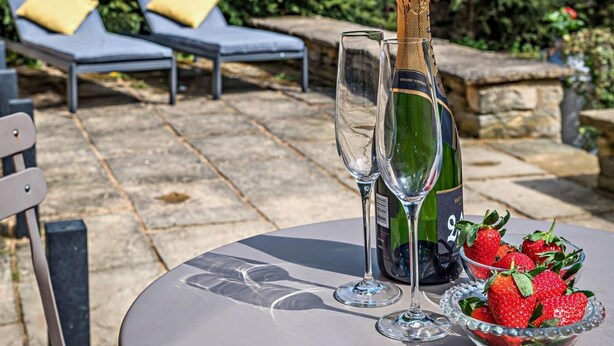 A table with a bottle of champagne, two glasses, and a bowl of strawberries. - 1 Bed in Lechlade (oc-31912) (Lechlade)