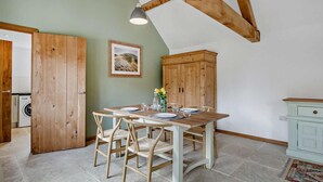 A dining area with a wooden table, chairs, and a hanging light fixture. - 1 Bed in Lechlade (oc-31912) (Lechlade)