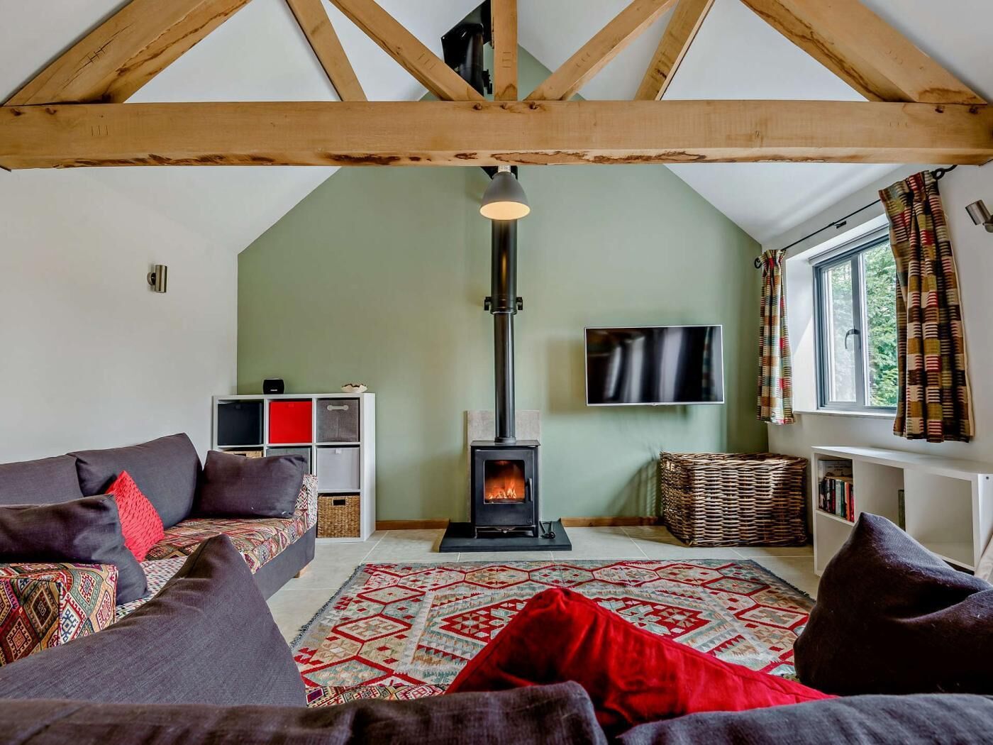 Una sala de estar acogedora con chimenea, un sofá, un televisor y una estantería.