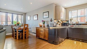 Une cuisine moderne avec un coin repas, des meubles en bois et de grandes fenêtres.