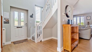 Un intérieur moderne avec un escalier, une horloge, un canapé et une étagère en bois.