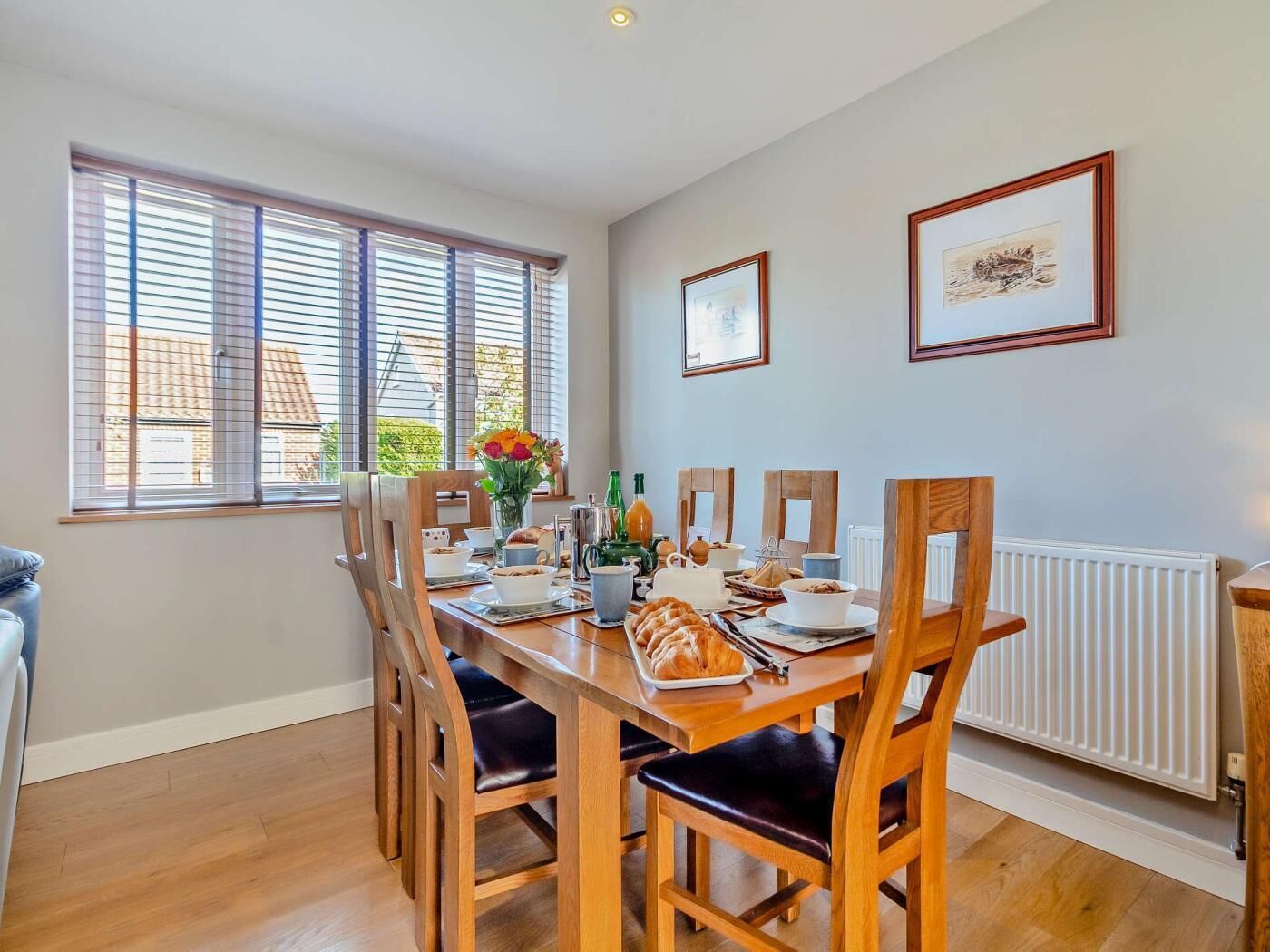 A dining area with a wooden table, chairs, and a window with blinds.