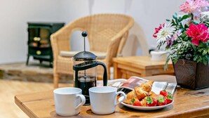 A breakfast setup with coffee, croissants, and strawberries on a wooden table. - 2 Bed in Barnstaple (oc-28959) (Newton Tracey)