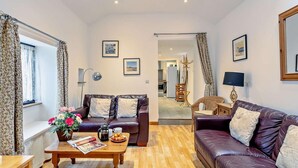 A living room with a sofa, coffee table, and a dining area with a table and chairs. - 2 Bed in Barnstaple (oc-28959) (Newton Tracey)