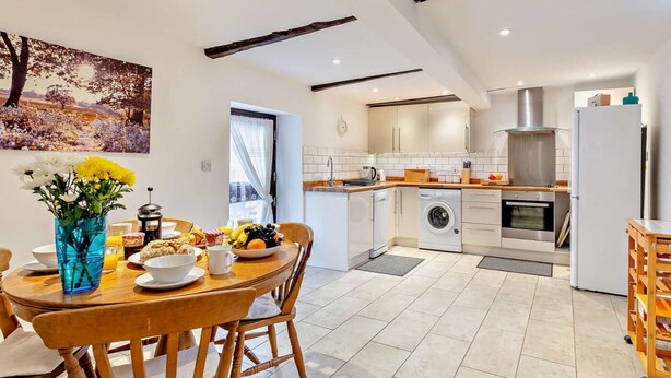 A modern kitchen with a dining area, a washing machine, and a refrigerator. - 2 Bed in Barnstaple (oc-28959) (Newton Tracey)