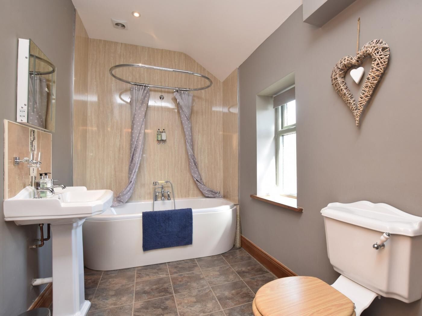 Un baño moderno con bañera, dos lavamanos, inodoro y ventana.