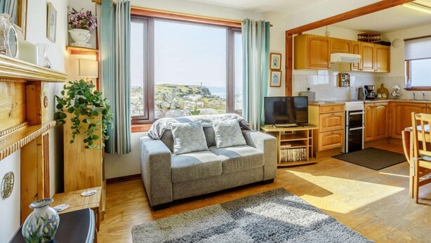 Una sala de estar acogedora con sofá, televisión y vistas al exterior.