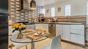A modern kitchen with a glass dining table, a refrigerator, a stove, and a sink. - 1 Bed in Forres (oc-32129) (Alves)