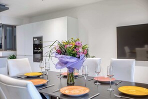 Una mesa de comedor puesta con platos, vasos y un ramo de flores.