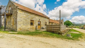 A stone building with a red-tiled roof, a wooden fence, and a dirt path. - 2 Bed in Middlesbrough (oc-tgchf) (Chop Gate)
