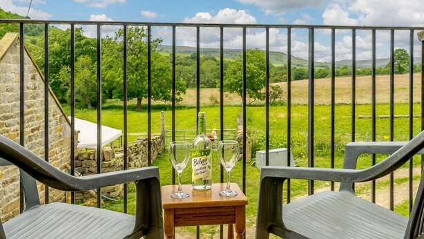 A balcony with a table, two chairs, and two wine glasses. - 2 Bed in Middlesbrough (oc-tgchf) (Chop Gate)