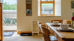 A dining area with a table, chairs, a window with a view of greenery, a mirror, and a door leading outside. - 2 Bed in Middlesbrough (oc-tgchf) (Chop Gate)