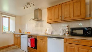 A kitchen with wooden cabinets, a dishwasher, a microwave, and a window with a view. - 2 Bed in Middlesbrough (oc-tgchf) (Chop Gate)