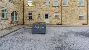 A stone building with multiple windows and a gravel courtyard. - 3 Bed in Consett (oc-29408) (Lanchester)