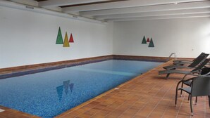 An indoor swimming pool with tiled flooring and lounge chairs. - Hof Arosa A-03 Appartement/Fewo,   4-Bettwohnung by Interhome (Arosa)