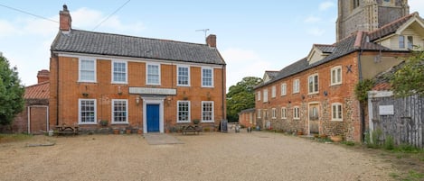 A traditional brick building with a blue door, a sign reading 'The White Lady,' and a gravel courtyard.