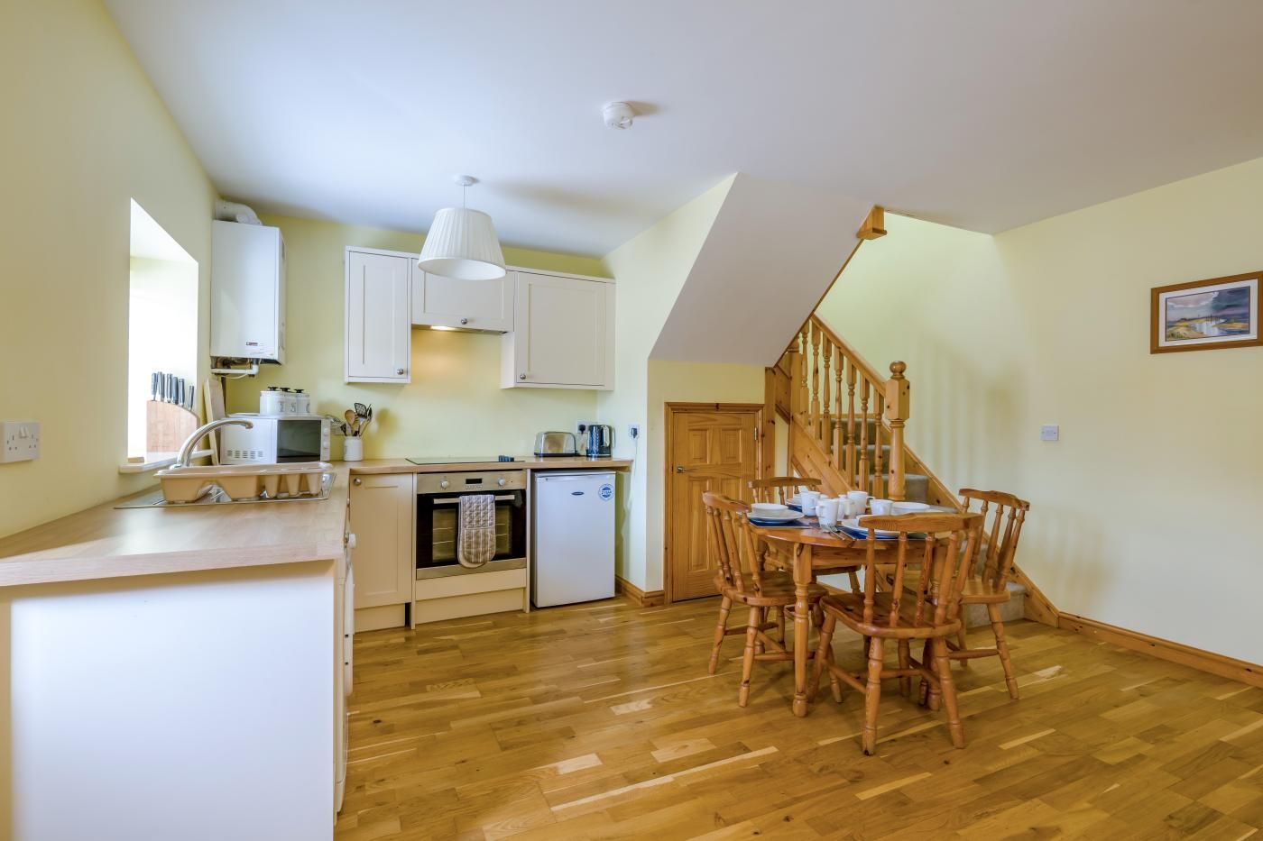 A kitchen with wooden cabinets, a built-in oven, a refrigerator, and a dining area with a wooden table and chairs.