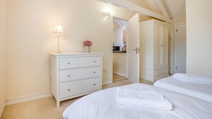 A bedroom with two beds, a dresser, a lamp, and a door leading to a kitchen. - 2 Bed in Shaftesbury (oc-28678) (Sedgehill)