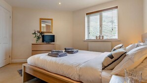 A bedroom with a bed, bedside table, TV, window, and a mirror. - 2 Bed in Truro (oc-36178) (Porthtowan)