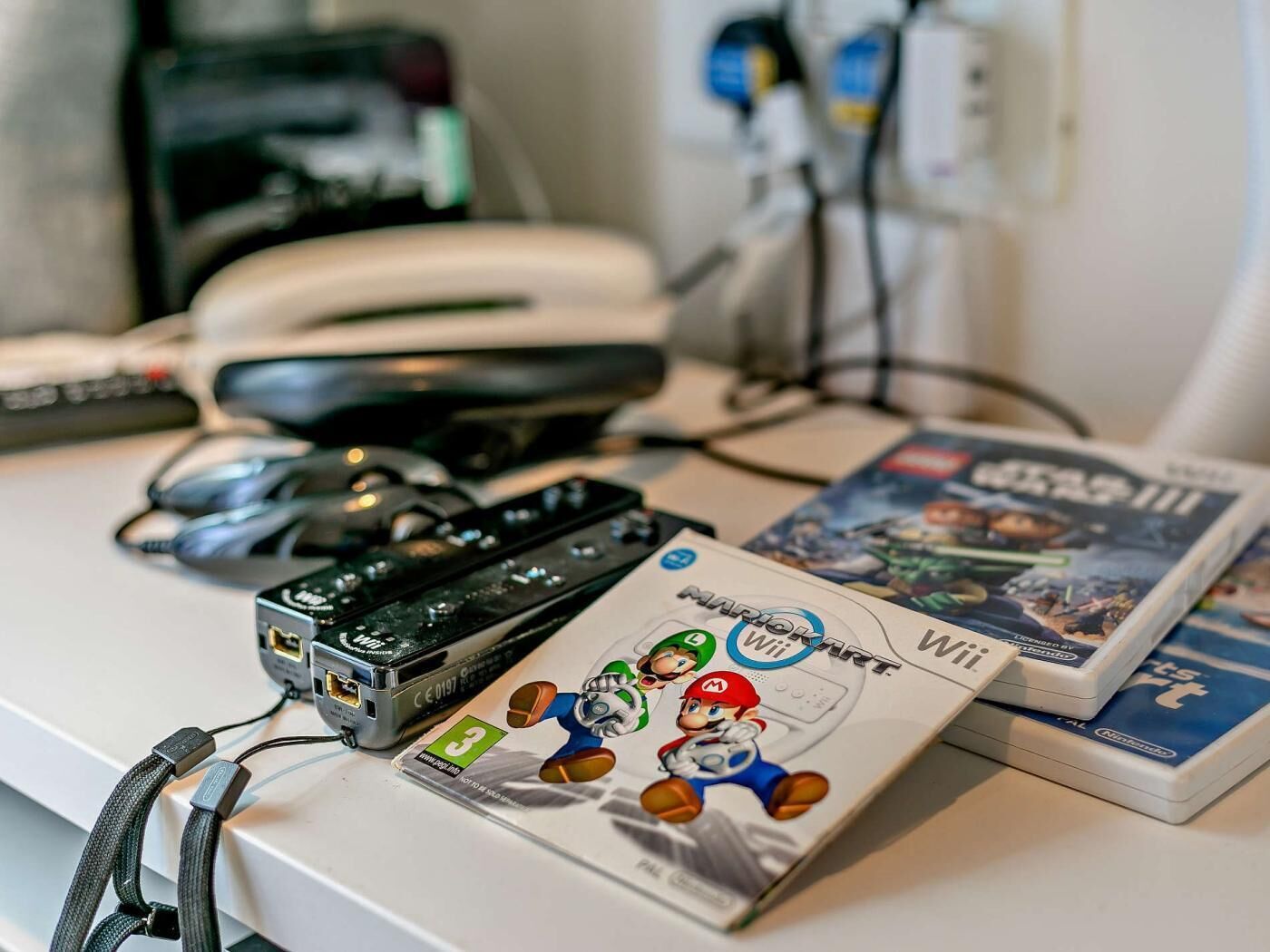 A desk with a Nintendo Wii console, a Wii remote, and a game controller.
