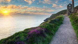 A coastal path with a stone structure, likely a historical building, leading to the sea. - 2 Bed in Truro (oc-36178) (Porthtowan)