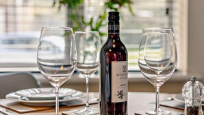 A table with wine glasses, a bottle of McGuig estate merlot, and a salt shaker. - 2 Bed in Truro (oc-36178) (Porthtowan)