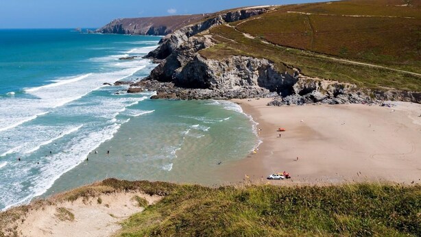 A coastal landscape with a beach, rocky cliffs, and clear blue sea. - 2 Bed in Truro (oc-36178) (Porthtowan)