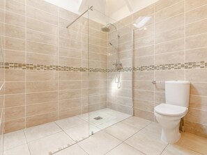 Une salle de bain moderne avec une douche à parois de verre, des toilettes et un carrelage au sol.